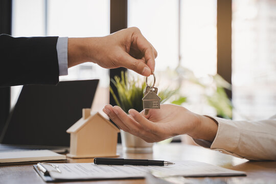 Realtor agent giving a key of apartment to new owner after signed lease agreement.
