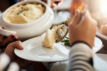 Hands, people and serve mashed potato on plate for thanksgiving feast, celebration and pov. Food, spoon and dinner at table with family for lunch, brunch or eating closeup on holiday in home together