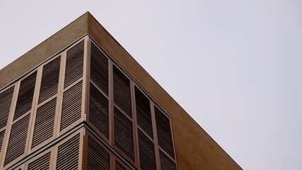 corner of postmodern minimalist building facade with wooden shutters