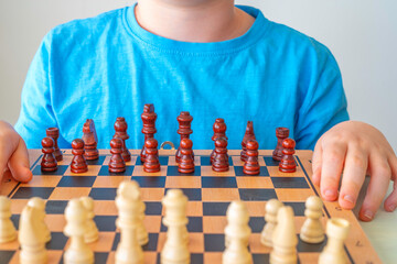 Chess pieces on the board and child sitting next to him. Chess class for children.