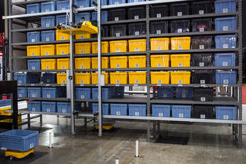 Autonomous robot picking materials from multi-layer rack in modern industrial warehouse.