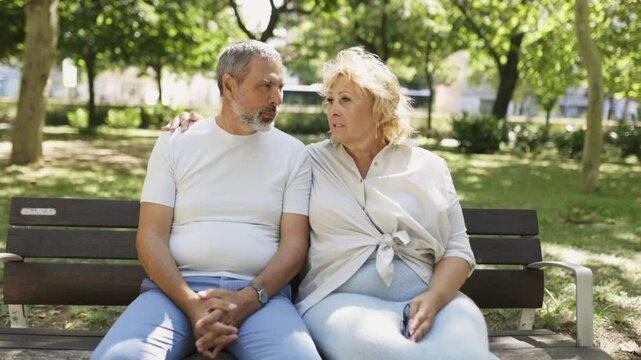 Engaging conversation between a senior couple seated on a park bench