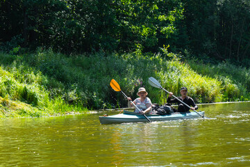 Family kayak trip for seigneur and senora. An elderly married couple rowing a boat on the river, a water hike, a summer adventure. Age-related sports, mental youth and health, tourism, active old age