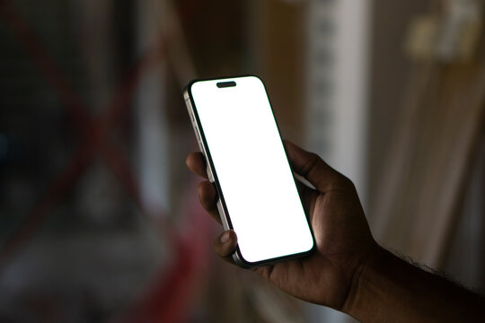 Young man Holding Smartphone with Blank White Screen in Modern Indoor Setting, Perfect for Mockups and Digital Content.