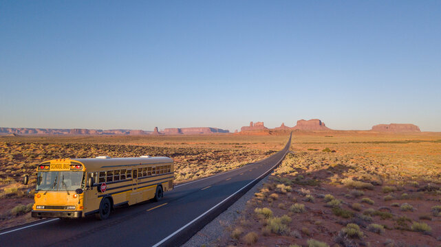 School bus drives on lonely desert road Monument Valley Forrest Gump 