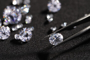 Tweezers with beautiful shiny diamonds on black fabric, closeup