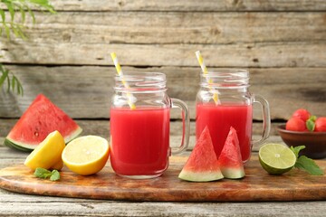 Tasty watermelon drink in mason jars and fresh fruits on wooden table