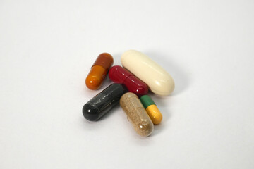 close up of multiple colorful medicine capsules on the white background isolated