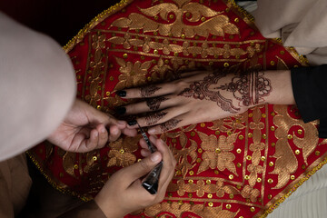 The process of painting henna on the bride's hands. There are many different names for henna tattoo...