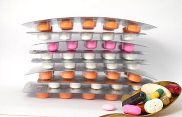 close up of medicine tablets in blister packaging and colorful drug in golden spoon on the white background