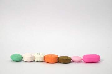 close up of colorful medicine tablets in a row on the white background