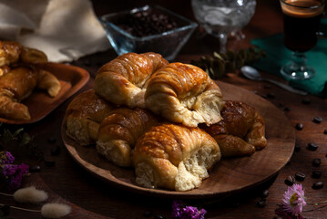 Butter croissants on a wooden plate with ingredients for breakfast or a snack and coffee beans 