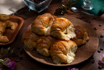 Butter croissants on a wooden plate with ingredients for breakfast or a snack and coffee beans 