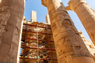 Archaeologists meticulously examining the colossal pillars of Karnak's Hypostyle Hall. They bring...