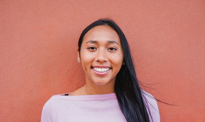 Portrait of native american woman smiling on camera with city wall in background - Indigenous girl...