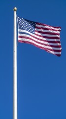 Obraz premium American flag waving proudly against a clear blue sky on a sunny day