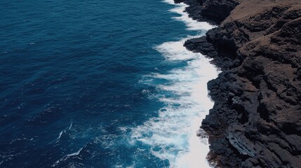 The breathtaking coastline of the French Riviera is captured at sunset, showcasing dramatic cliffs where waves crash and sea foam dances on the vibrant blue ocean