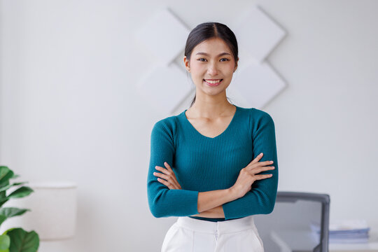 Portrait of young Asain business woman standing with confidence expression arms crossed and looking at the camera in the office.