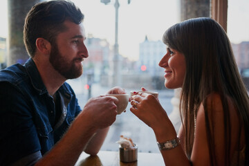 Coffee shop, happy and couple in conversation with drink, caffeine beverage and cappuccino in cafe. Dating, love and man and woman relax in restaurant for bonding, relationship and romance on weekend