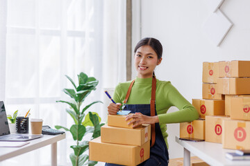 SME business asian entrepreneurs small in Asia Write shipping information on a cardboard box in home office. Small business sme operators preparing to ship to customer