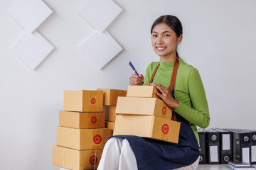 SME business asian entrepreneurs small in Asia Write shipping information on a cardboard box in home office. Small business sme operators preparing to ship to customer