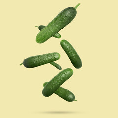 Whole ripe cucumbers falling on dark beige background
