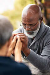 Fototapeta premium Holding hands, couple and faith of people, table and religion of mature man, glasses and respect. Outdoor, Christian and worship of God in park, praying and praise of holy spirit, together and grace