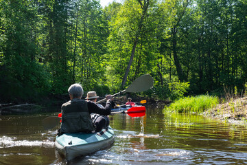 Group kayak trip for seigneur and senora . An elderly couple And adult rowing boat on the river, a water hike, a summer adventure. Age-related sports, mental youth and health, tourism, active old age