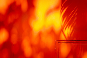A red wall with orange shadows on it. The wall is covered in graffiti and has a lot of texture
