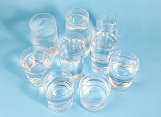 Food and drinks abstract background, many glasses of clean drinking water in transparent glass on light blue background. 