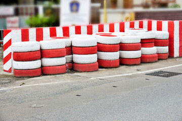 A row of tires are stacked on the side of the road. The tires are red and white
