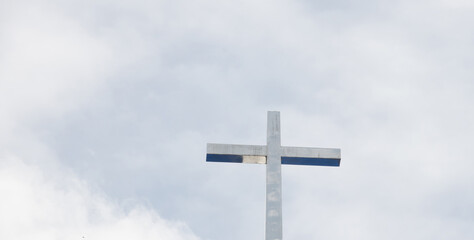 A large cross is standing tall in the sky. The sky is cloudy and the sun is not visible