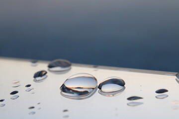 drop of water, water droplets reflecting onto mirror, warm sunset visible in the water droplets, macro photography, morning dew