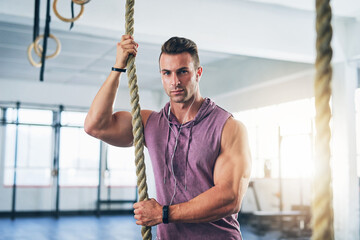 Rope, fitness and man in gym, portrait and exercise with training, wellness and endurance. Face, athlete and healthy guy in facility, cardio workout and energy with mindset, confidence and challenge