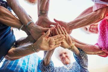 Senior people, friends and hands stack outdoor in low angle for community and retirement activity. Elderly group, circle and huddle outside for support, solidarity and nursing home games as teamwork