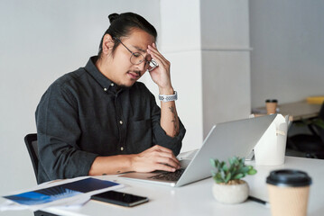 Asian man, headache and laptop glitch in office, stress and 404 error or burnout for bankruptcy. Male person, glasses and frustrated for proposal or project, depression and anxiety for business