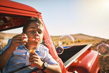Child, vacation and blowing bubbles by window on road trip in summer, memory or journey on...