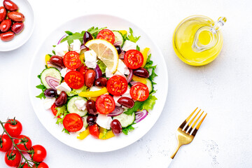 Greek salad with white cheese, olives, tomatoes, paprika, cucumber and onion. White background, top view