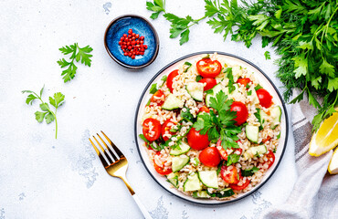 Bulgur salad with tomatoes, cucumbers and parsley.. White background, top view