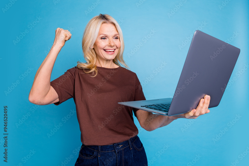 Poster Photo of positive lovely retired woman wear trendy brown clothes hand fist yes isolated on blue color background