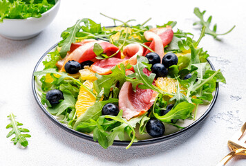Tasty salad with grilled duck and juicy orange, blueberry and arugula on white background, top view