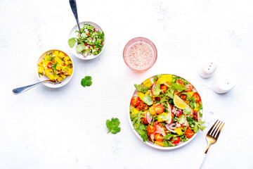 Mexican salad with grilled chicken and mango salsa, tomato, cilantro, onion, lime juice and lettuce, white background, top view