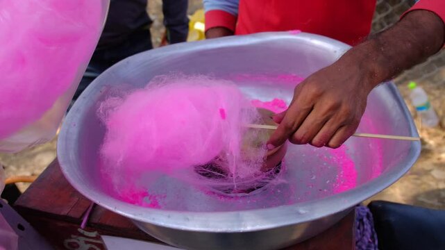 Pink cotton sweet in Candy Machine. Fluffy sugar product on festival. Sweet cotton dessert preparation, pink cotton candy at a street fair food stall.