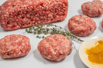 Ground beef patties on the background of spices and herbs.