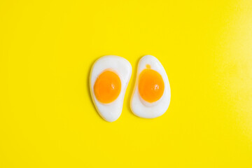 Jelly candy in the form of sunny side up egg on yellow background.