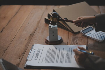 Real Estate Law, Home Insurance, property Tax, Auction and Bidding concepts. small toy house model with gavel justice hammer on desk in courthouse.