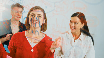 Professional business team brainstorming and working together about marketing project. Female caucasian leader writing idea on stick note while coworker present her idea confidently. Immaculate.