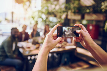 Person, hands and phone with camera at restaurant for photography, picture or team building moment. Closeup, group or memory on mobile smartphone for event or social gathering together at indoor cafe