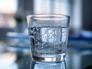 Microplastics, or minuscule plastic fragments, in a glass of water. The concept of drinking water being polluted with microplastics © Emanuel