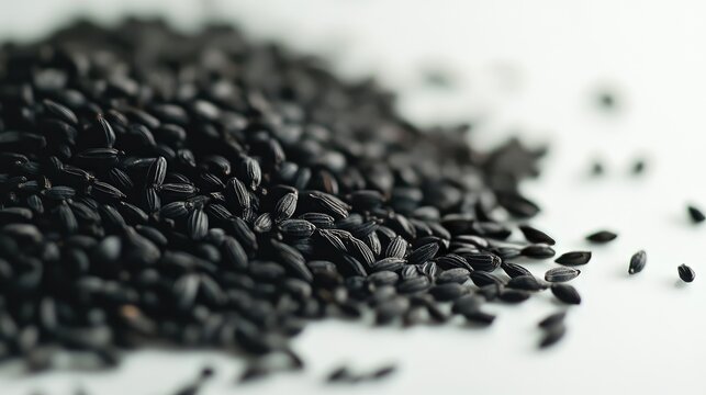 Close-up of black cumin seeds (Nigella) scattered on a white surface, focusing on their unique texture and color, no people.
